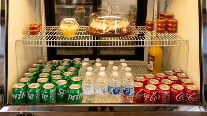 A refrigerated display case filled with drinks, desserts, and small containers of sauce.